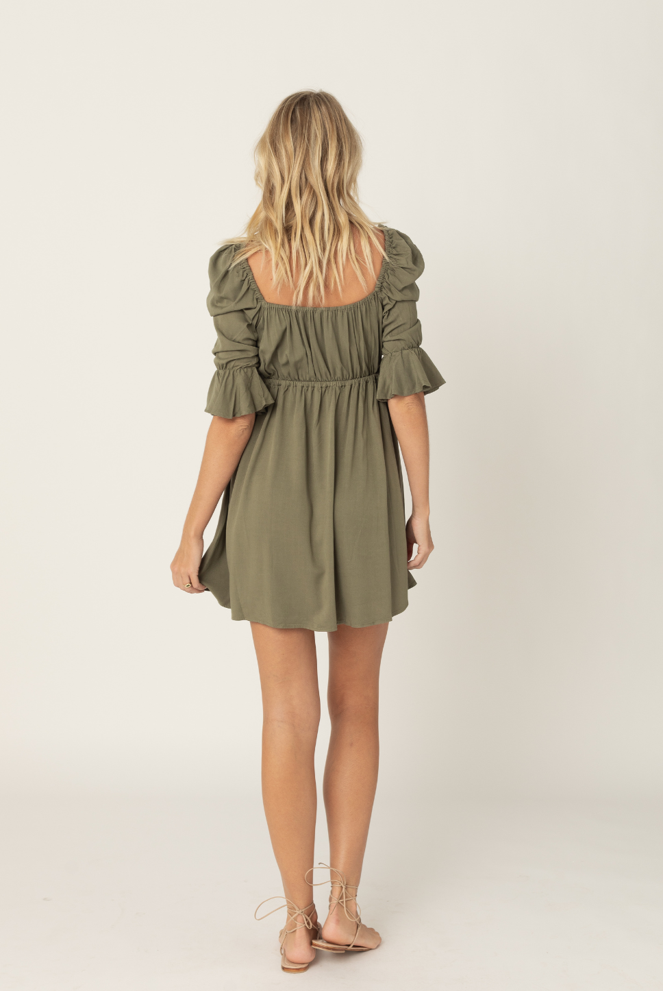 Khaki green mini empire waist dress with a bow tie enclosure in the front. Elastic bust and sleeves for a forgiving fit. Can be worn off the shoulder or backwards. Is breastfeeding and bust friendly.